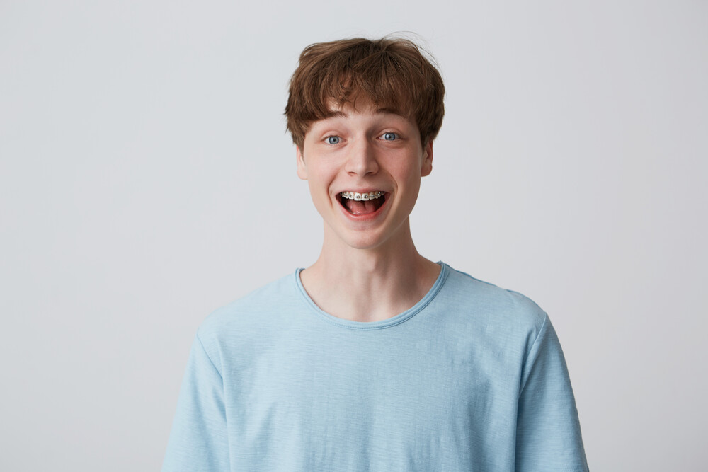 people,  male,  man,  guy,  short,  disheveled,  hair,  young,  youth,  20's,  european,  braces,  teeth,  appearance,  copyspace,  isolated,  white,  studio,  background,  indoor,  dressed,  blue,  casual,  tshirt,  looks,  directly,  camera,  portrait,  closeup,  cute,  happy,  nice,  kind,  student,  teenager,  attractive,  standing,  feels,  natural,  unconstrained,  informal,  easy,  emotions,  expression,  amazed,  excited,  surprised,  shouting