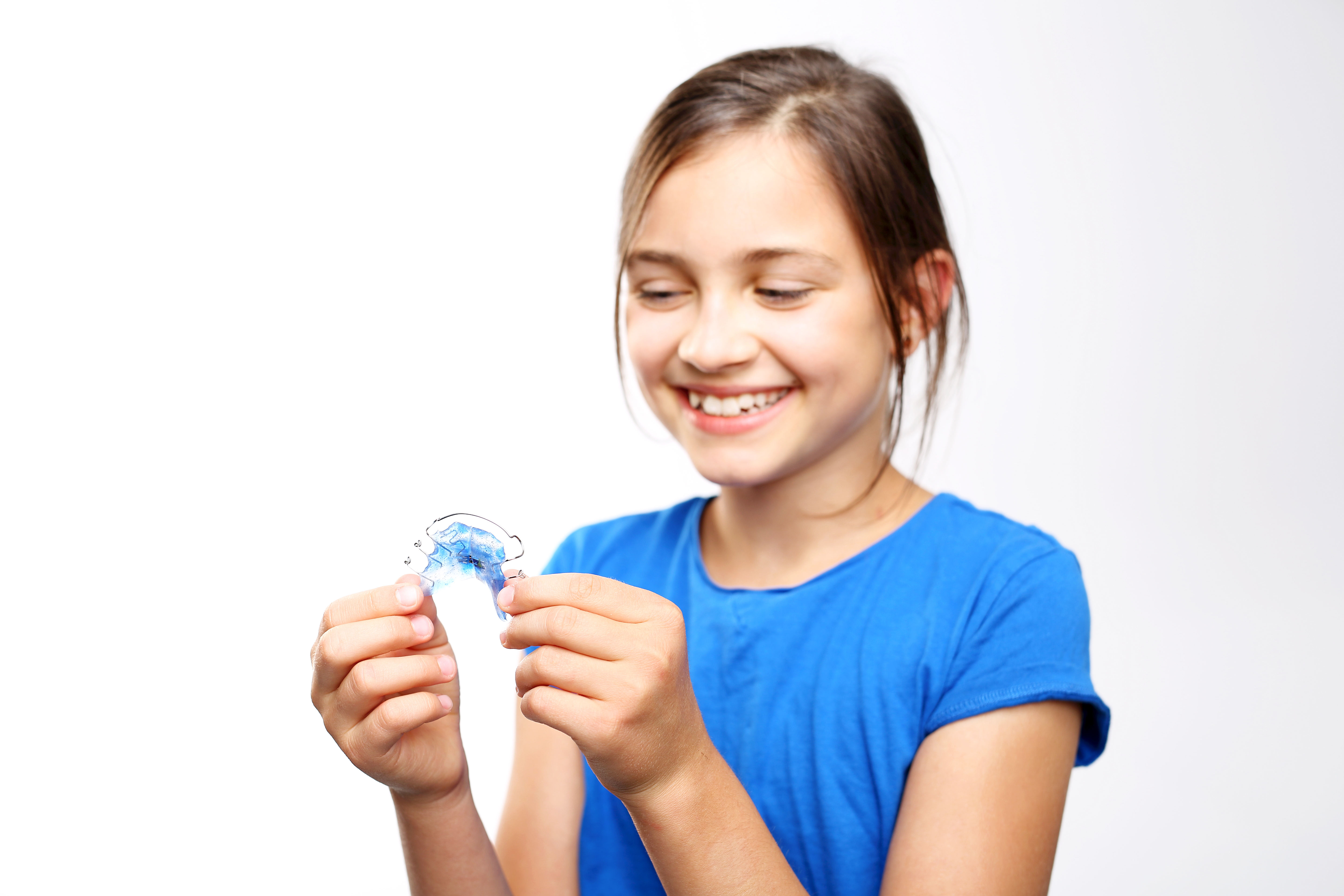 girl holding a retainer, happy, teeth